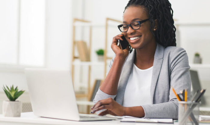 woman looking at laptop while talking on phone