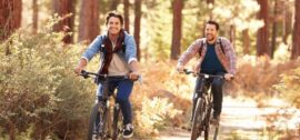 Two younger men riding bikes in the forest